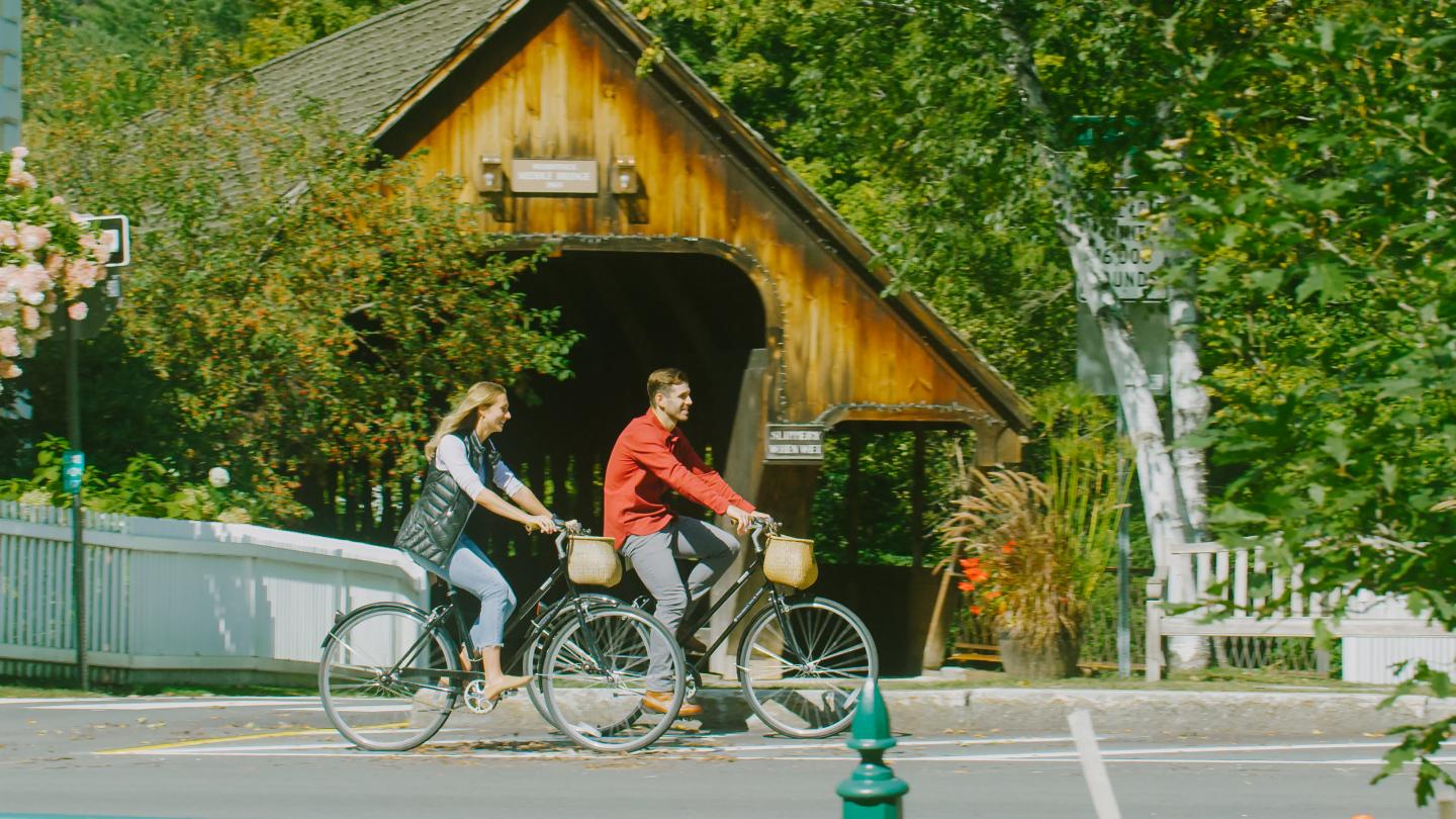 a couple riding bikes in front of a covered bidge