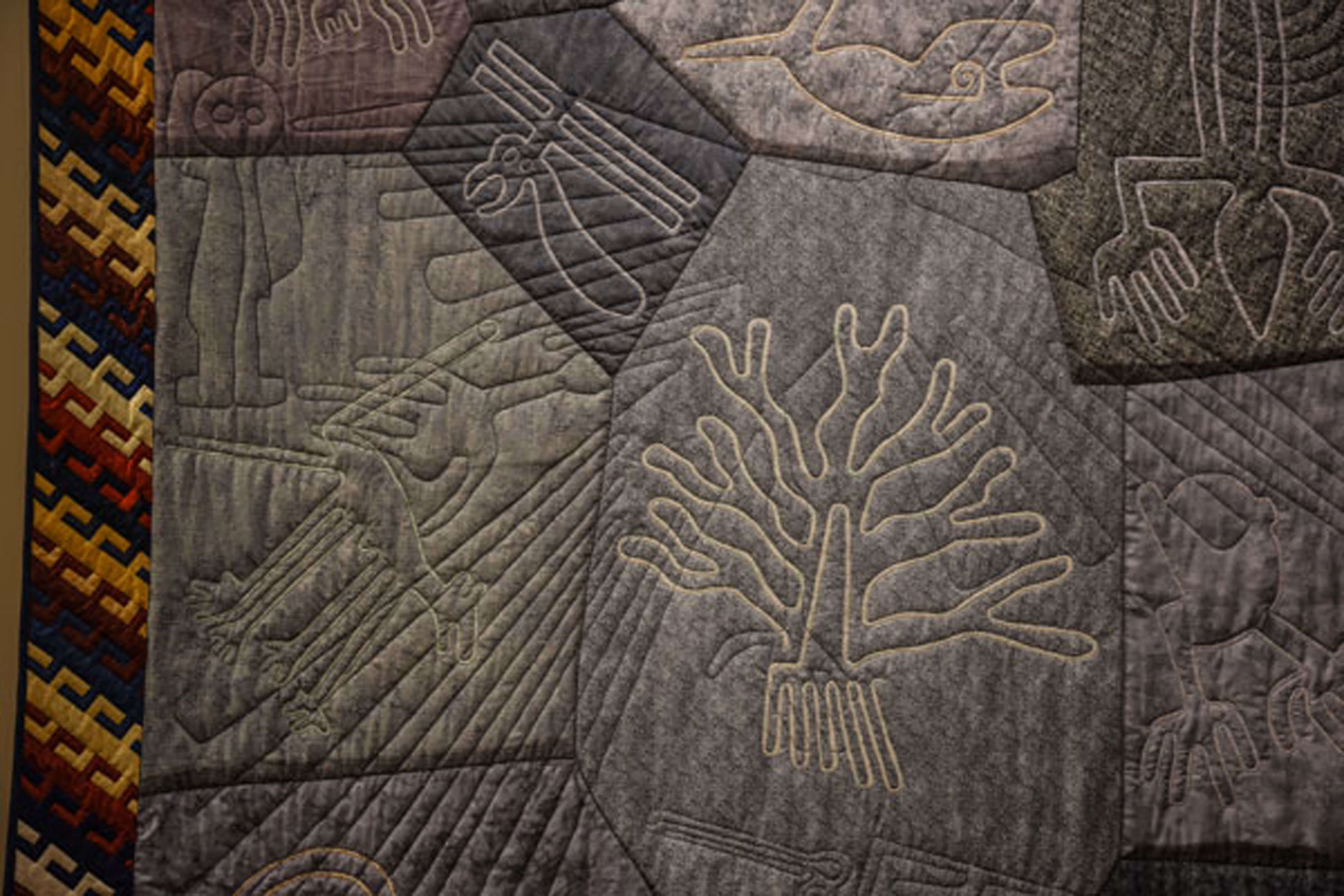 Quilt with tree like patterns sewn on.