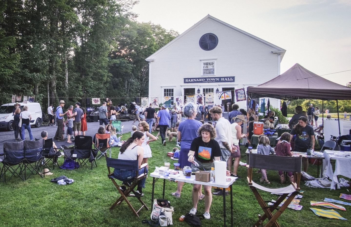 A photo of the front of Barnard Town Hall with Barnard Street Dance happening in front of it. There are tents with people serving drinks, a face painting booth, people dancing in front of a band, and art making.