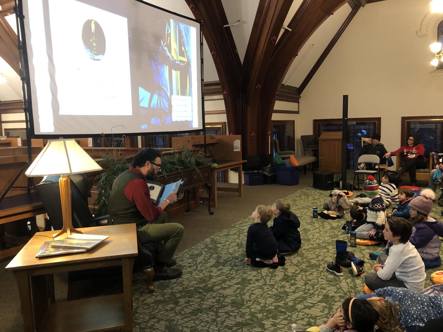 Adrian reading to children with images from book projected