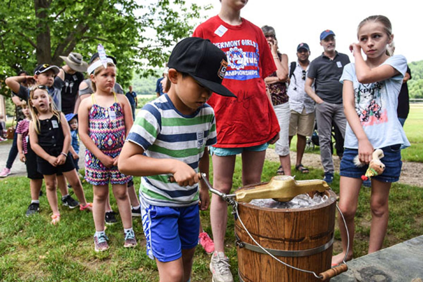 Children making ice cream using a crank.