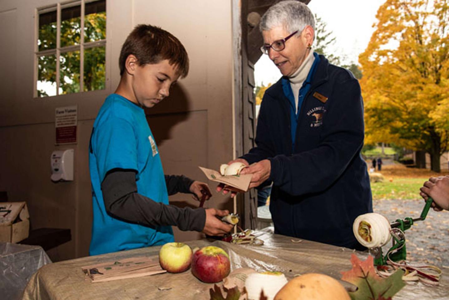 Child learning to use an apple peeler and corer.