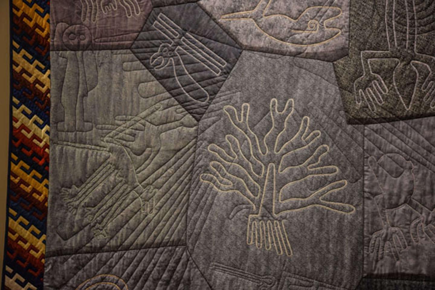 Quilt with tree like patterns sewn on.