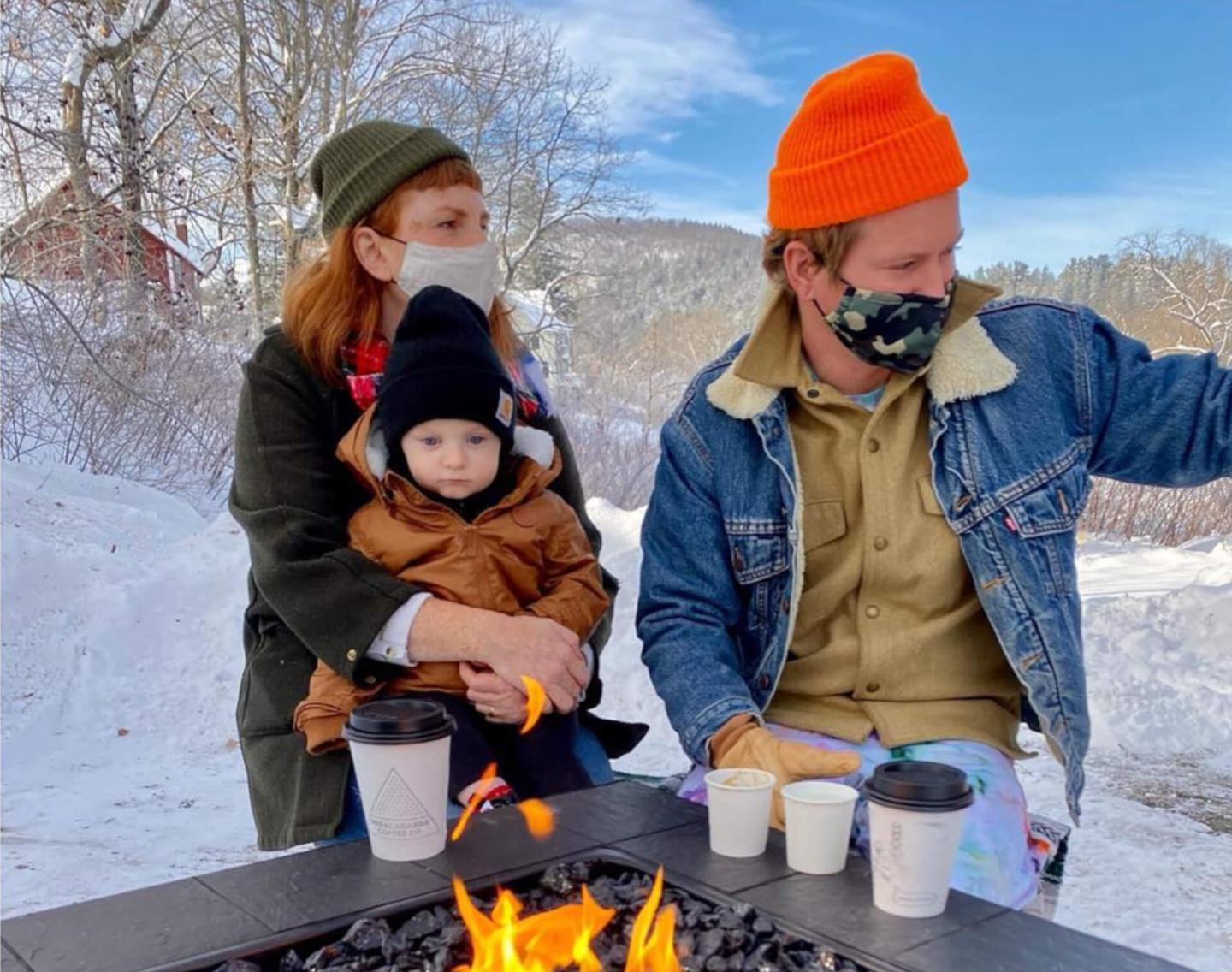 family sitting by fire with coffee