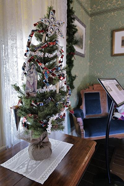 Small Christmas tree on a table in a room with green wallpaper.