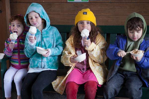 Four kids eating ice cream wearing colorful clothing.