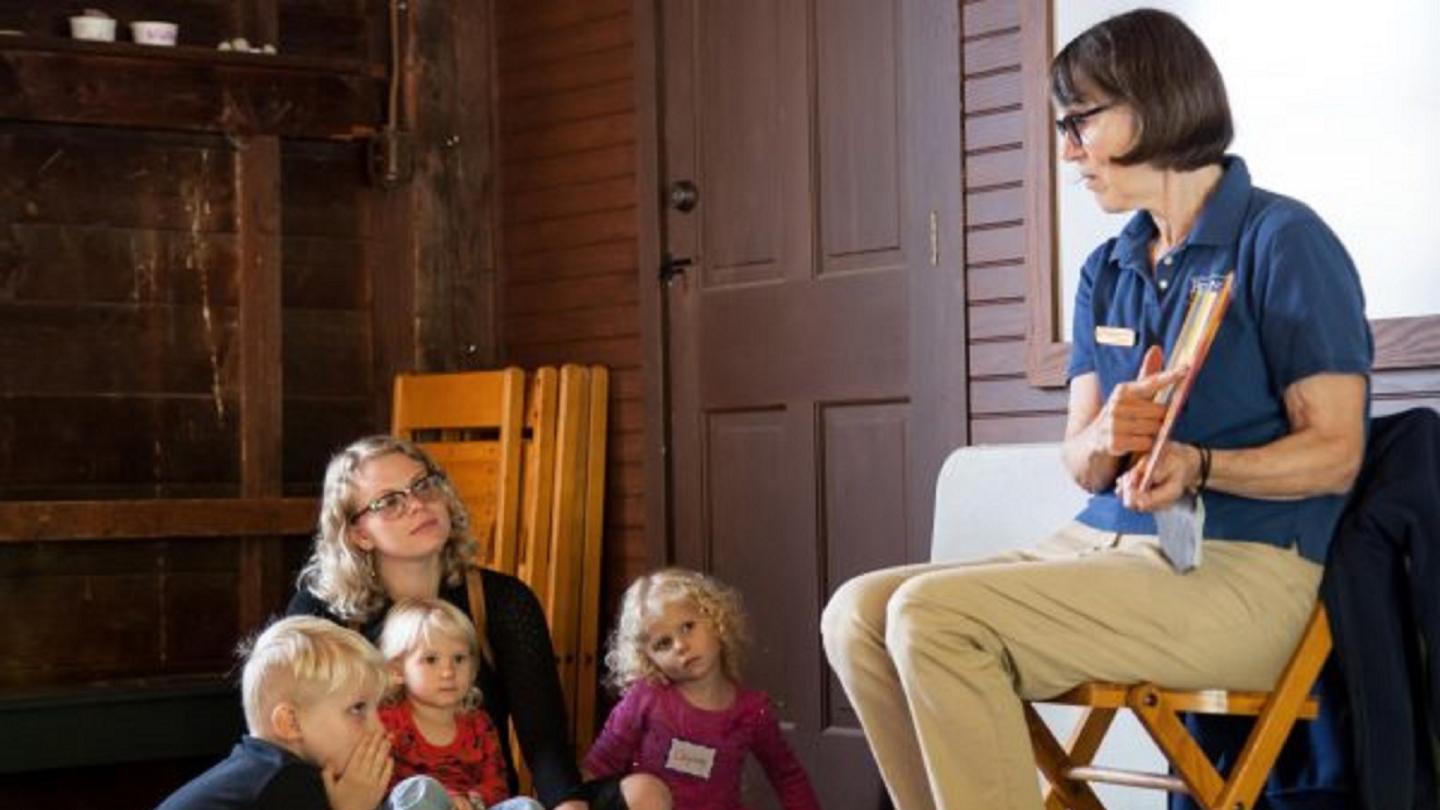 Kids sitting on the floor listening to a story being read.