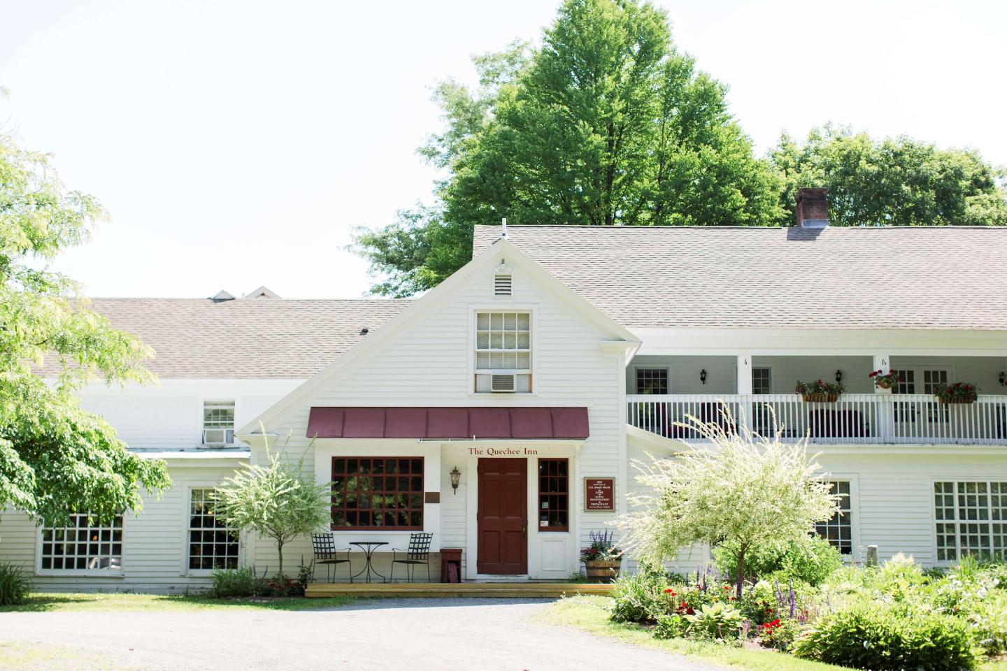 Photo of white inn with red door and balcony.