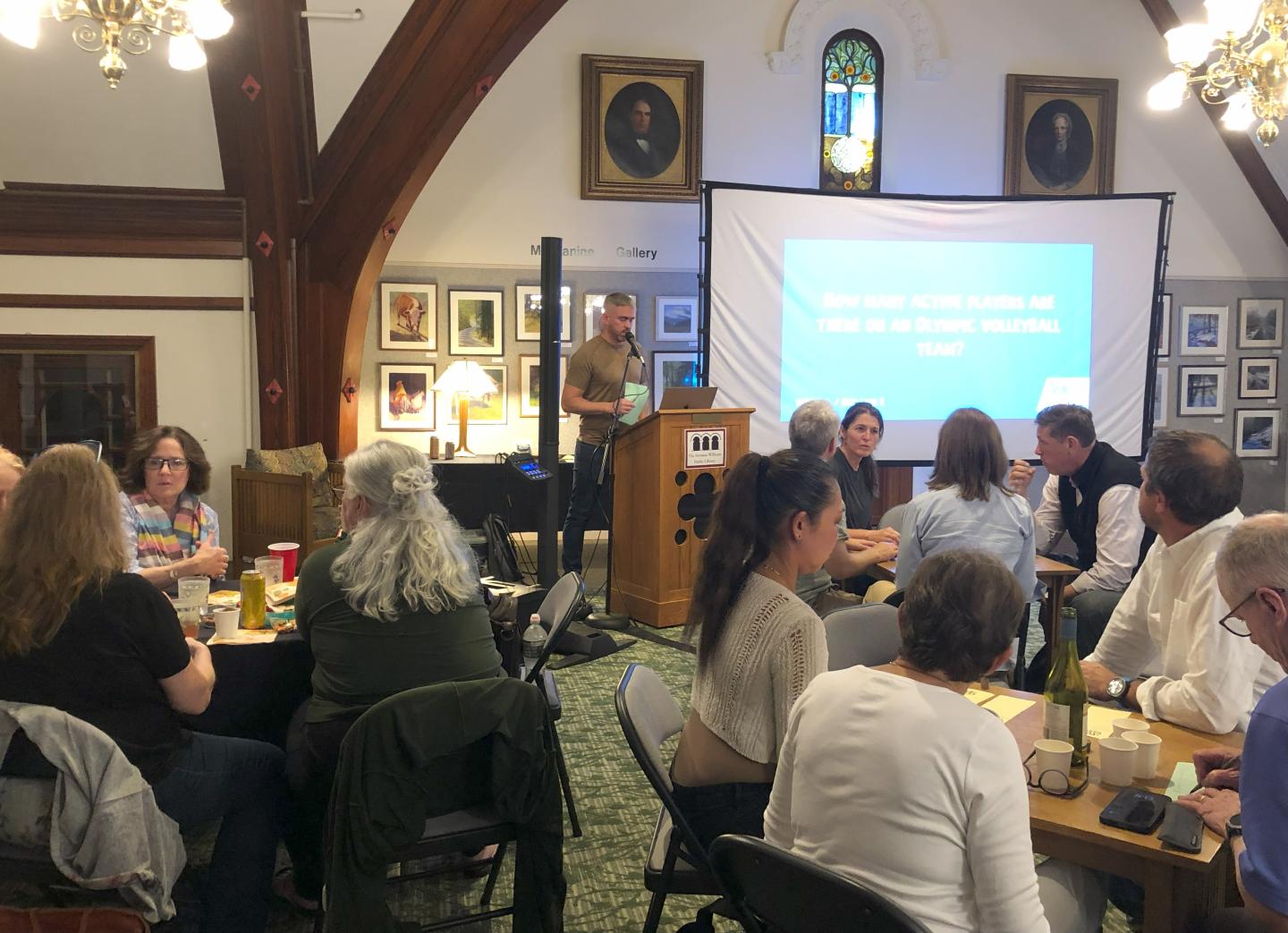 Trivia game in the library with screen and moderator at lectern.