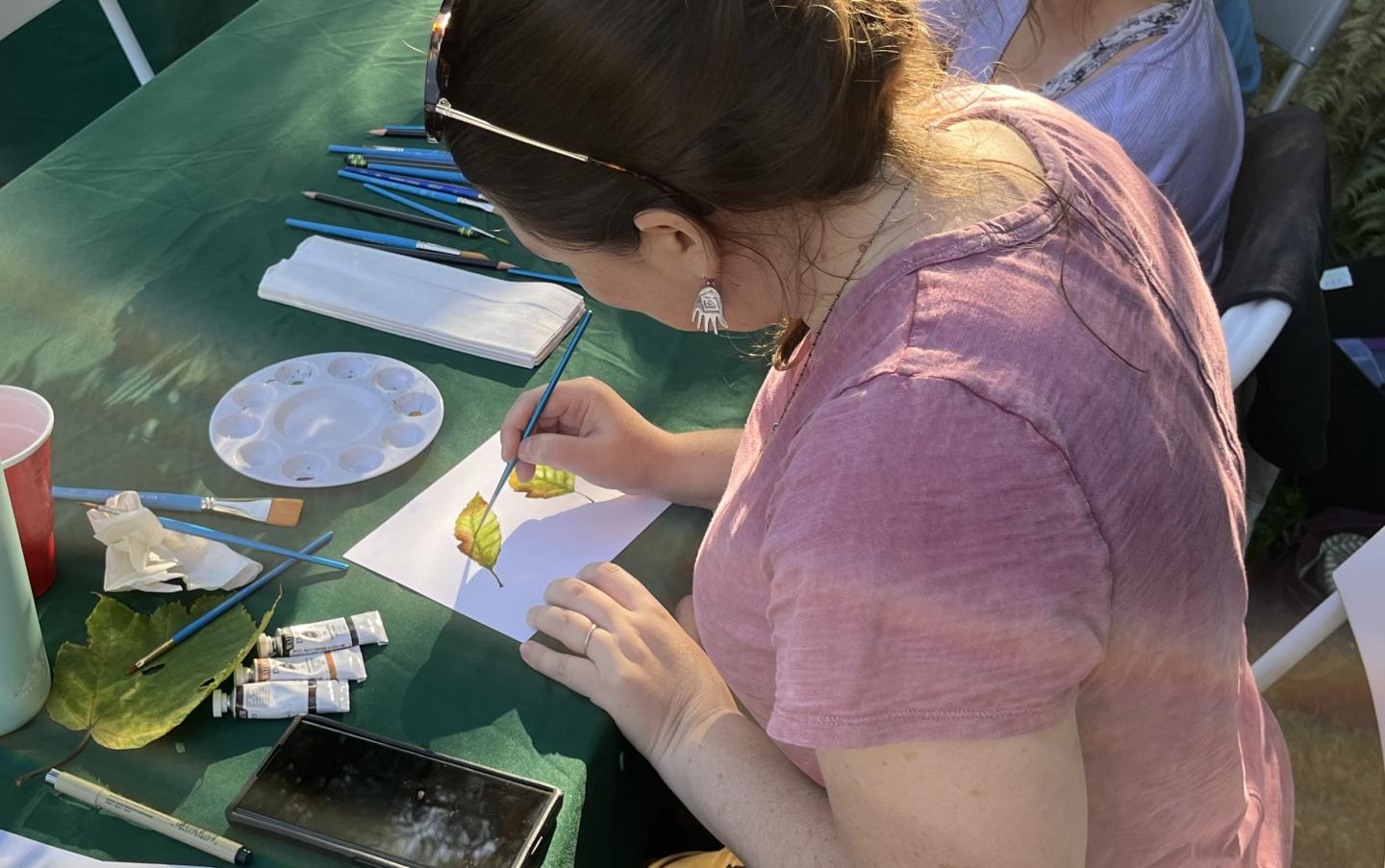 over the shoulder of artist painting watercolor leaves