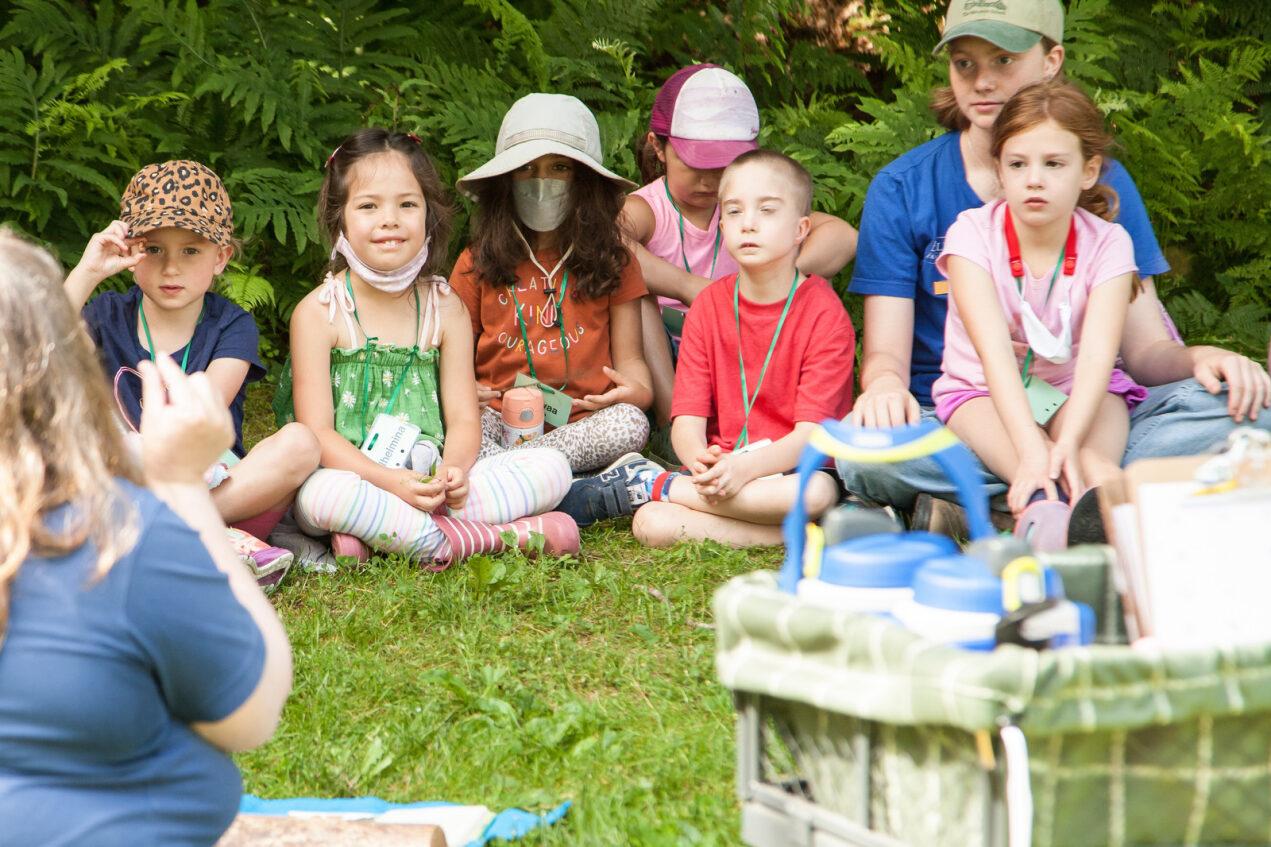 Kids sitting on a lawn listening to a story.
