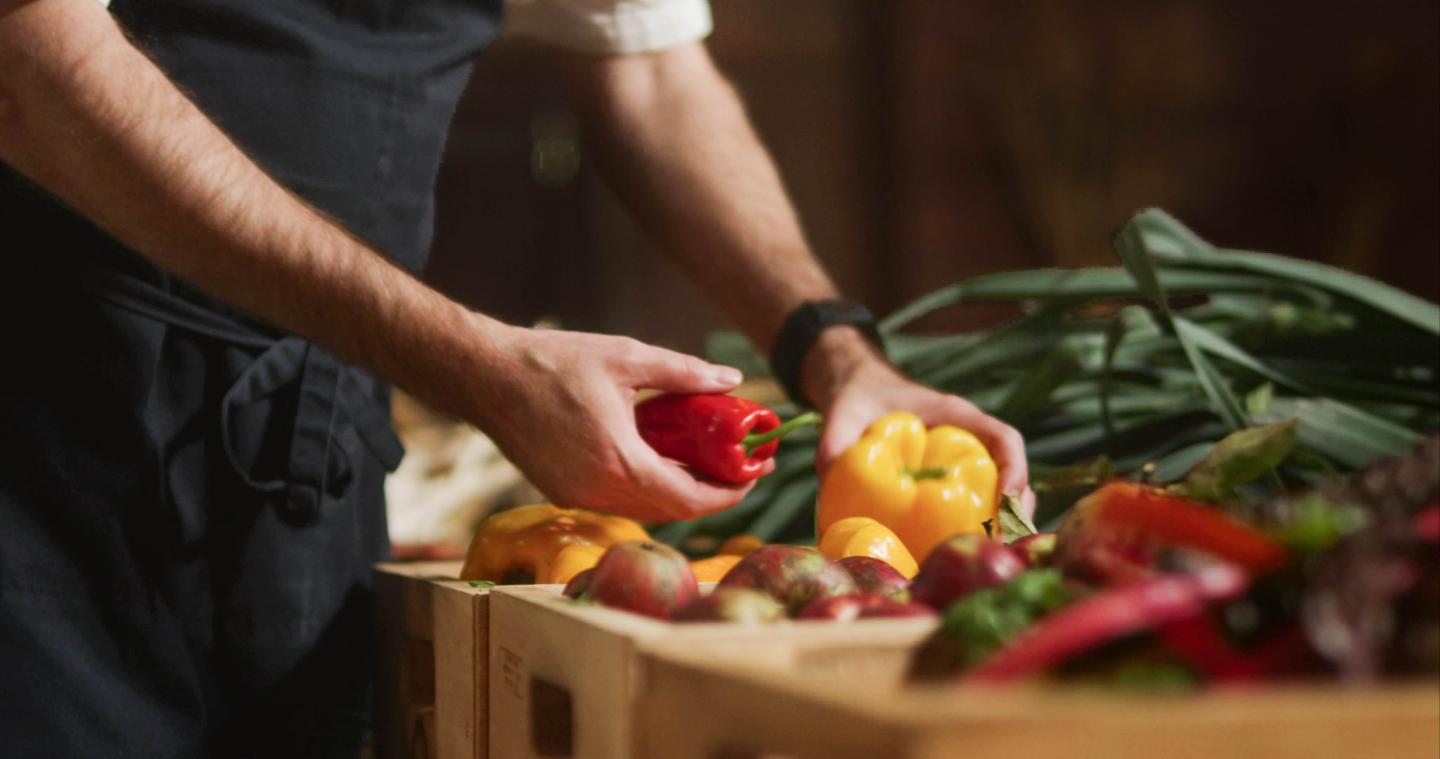 Chef picking up yellow and red bell peppers