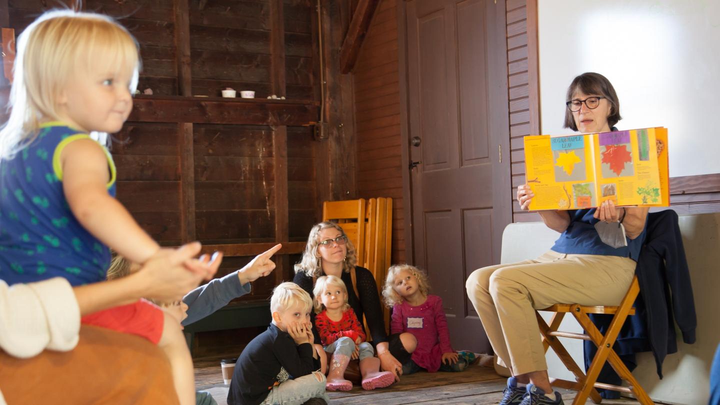 Kids sitting on the floor listening to a story being read.
