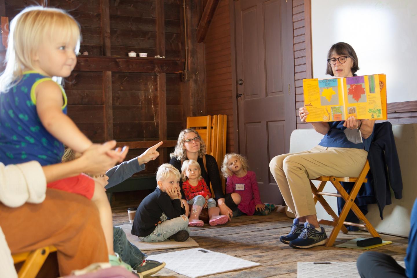 Kids sitting on the floor listening to a story being read.