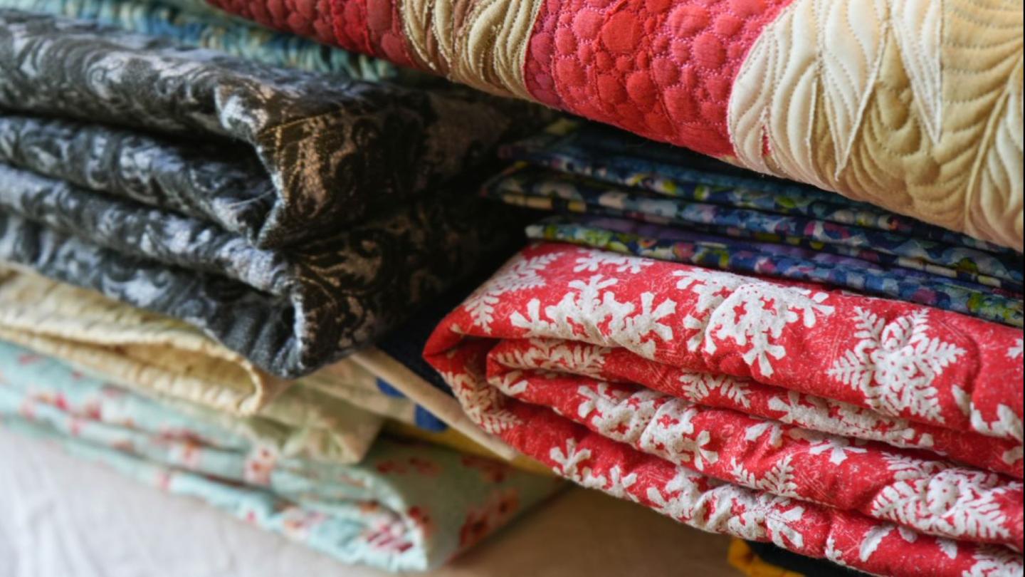 Several folded colorful quilts.