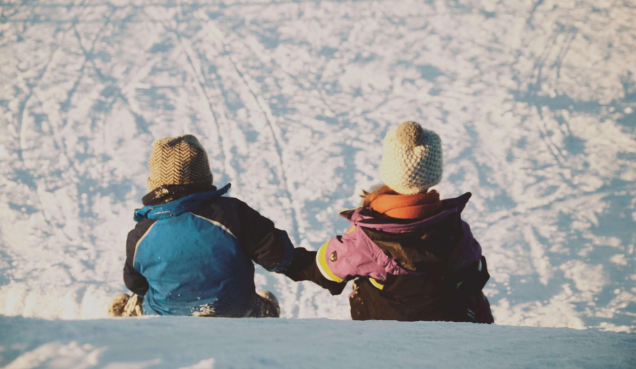 Two kids sledding in snow