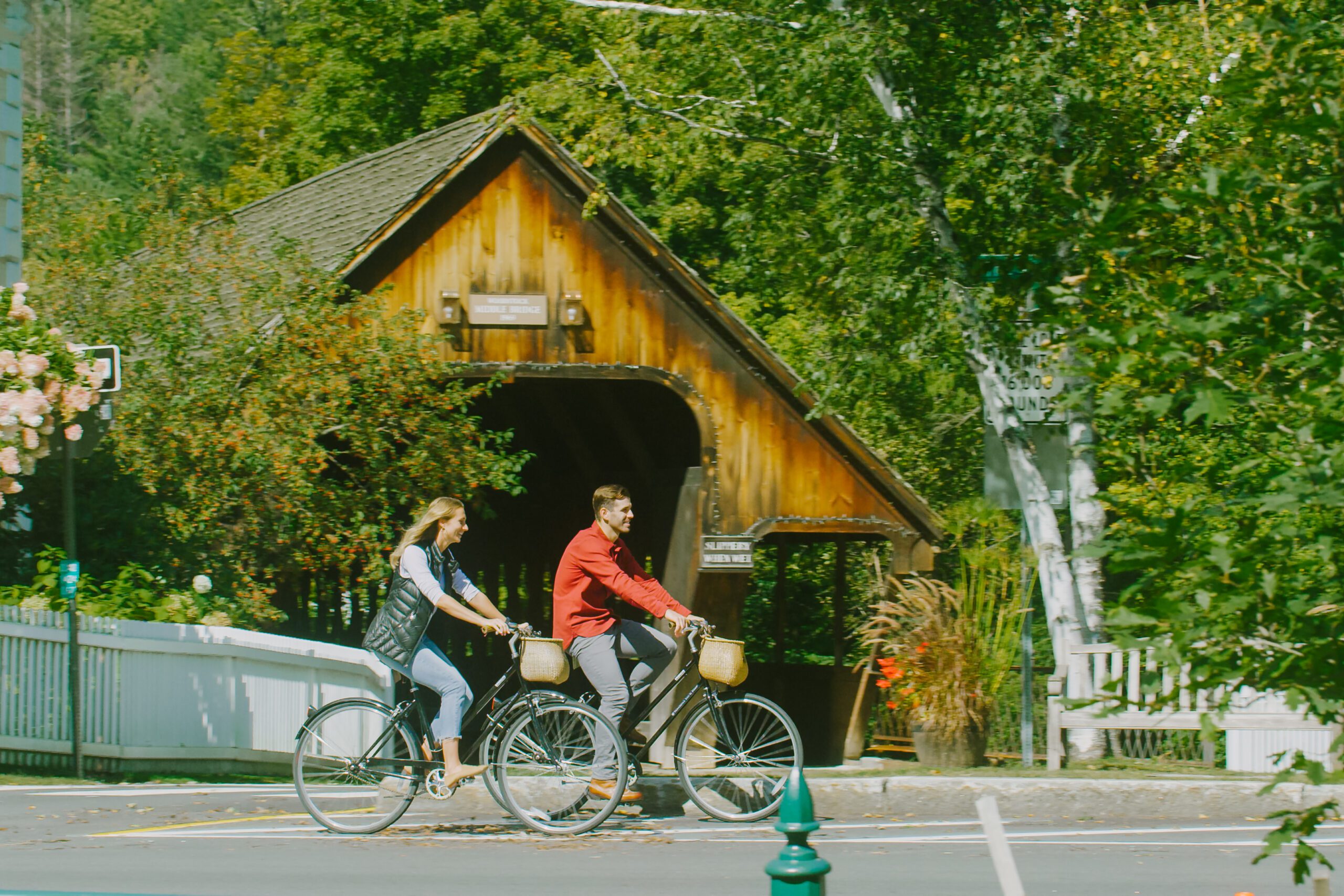 a couple riding bikes in front of a covered bidge