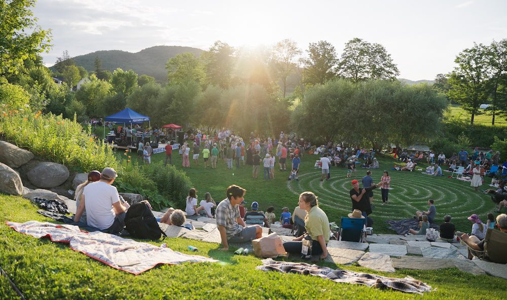 Concert attendees lounging at the East End Park during summer in Woodstock, VT.