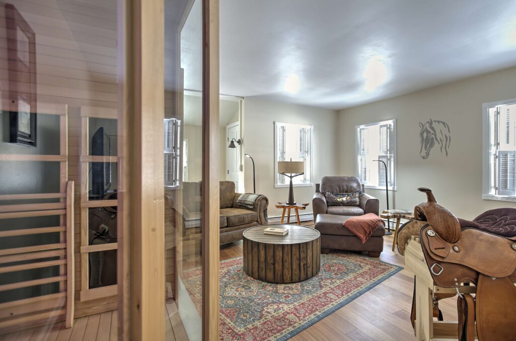 living room with decorative saddle, sauna, coffee table, leather armchair, bright windows