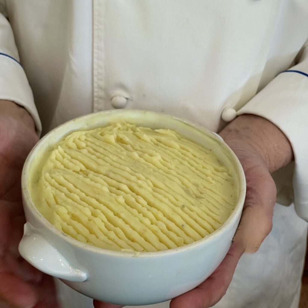 A cook gesturing proudly about the shepherd's pie she just made!